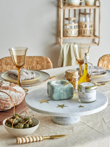 white marble cake stand with 3 brass stars imbedded on dining table